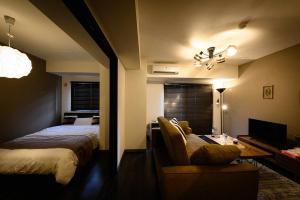 Kita-hamachōBaycourt Otaru的一间卧室配有一张床、一张沙发和一台电视。