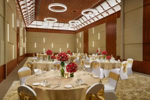 瓦亚纳德Taj Wayanad Resort & Spa, Kerala的宴会厅配有白色的桌椅和红色的鲜花