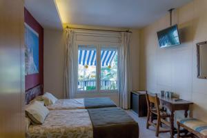 锡切斯加雷翁酒店的一间卧室配有一张床、一张书桌和一个窗户。