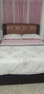 日得拉AZhomestay的一张带棕色床头板和粉红色及白色床单的床