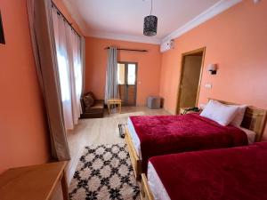 瓦尔扎扎特Ksar Ben Youssef的一间卧室设有两张床,拥有橙色的墙壁。