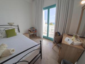 克里希阿克提阿玛丽利斯海滩酒店的一间卧室配有一张床、一张书桌和一个窗户。
