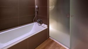 卡斯特尔德费尔斯普拉亚费尔斯酒店的带浴缸的浴室和墙上的电话
