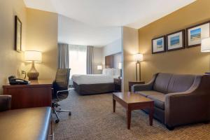 弗利弗利北部湾岸康福特套房酒店的酒店客房配有一张床、一张沙发和一张书桌。