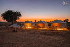 斋沙默尔Helsinki Desert Camp的日落时分在沙漠中的一组帐篷