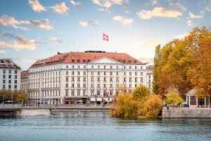 日内瓦日内瓦贝尔格四季酒店的一座在河岸上悬挂有吊旗的建筑物