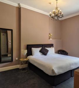 南安普敦Blue Keys Hotel Southampton的一间卧室配有一张带镜子和吊灯的床。