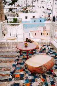 丹吉尔The Riad Hostel Tangier的阳台配有桌椅,猫睡在地毯上