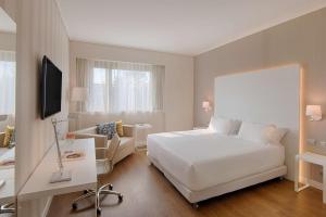 都灵NH都灵中心酒店的酒店客房配有白色的床和沙发。
