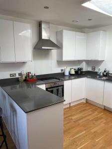 伊灵Lovely 2-bed flat with well equipped kitchen的厨房配有白色橱柜和黑色台面