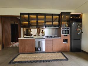 茂物Villa Vimala Hills Semeru的厨房配有木制橱柜和黑色冰箱。