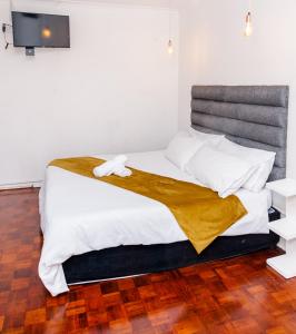 德班Nkosazana Guest House的一间卧室设有一张大床,铺有木地板