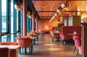 格洛米茨aja Grömitz的餐厅设有红色的椅子和桌子以及窗户。