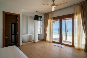 沙美岛Diamond Beach Resort的一间卧室设有一张床和一个浴缸,享有海滩美景