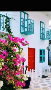 黎明之村Greek Bay的白色的建筑,有红色的门和粉红色的花朵