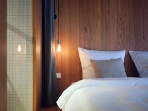 瓦尔德基尔希ArtBau Designhotel的卧室配有白色的床和木制床头板
