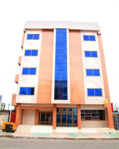 科托努HOTEL MAVILLA Cotonou的街道上高大的建筑,有蓝色的窗户