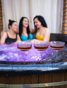文尼察Hotel DENINNA的三个妇女在带酒杯的热水浴池中
