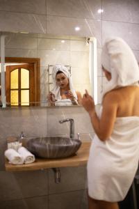 文尼察Hotel DENINNA的站在浴室水槽前的毛巾里的一个女人