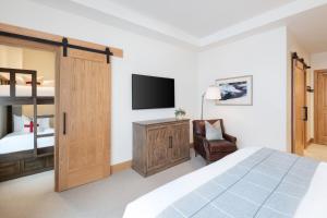 阿尔塔The Snowpine Lodge的一间卧室配有一张床、一台电视和一把椅子