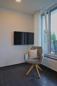 梅肯博伊伦STERK Apartments - idyllisch - modern - stilvoll的椅子坐在墙上的电视室里