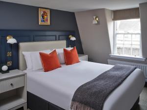巴斯Henrietta House, a member of Radisson Individuals的卧室配有带橙色枕头的大型白色床