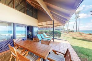 蒙内罗亚Kepuhi Beach Cottage 2B的一个带木桌和椅子的庭院和大海