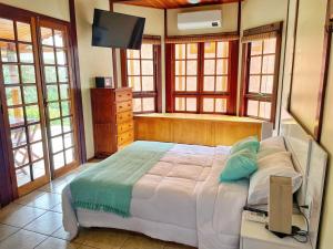 伊加拉塔Chalé das Águas的一间卧室设有一张床、一台电视和窗户。
