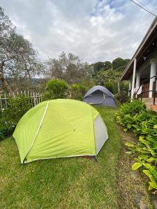 下博克特Agartha Hostel的两顶帐篷,坐在房子旁边的草上