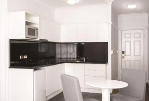 布里斯班布里斯班安扎克广场阿迪纳公寓式酒店的厨房配有白色橱柜和白色的桌椅