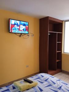 洛哈Hotel Residencial Miraflores的卧室配有一张床,墙上配有电视。