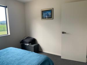Guest Suite in Peaceful Location Roxburgh的卧室配有一张床和一把椅子,靠窗