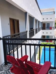 Cuatrociénegas de CarranzaHotel Casa Nodin的一个带红色椅子的阳台和一个游泳池