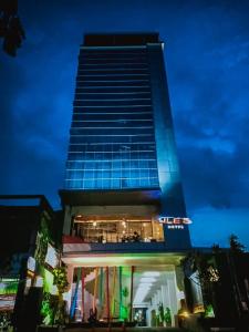 美娜多JLE'S酒店的一座高大的建筑,上面有蓝色的灯光