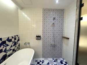 高雄温式旅所 的浴室设有浴缸以及蓝色和白色瓷砖淋浴。