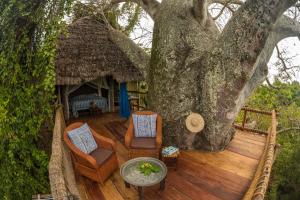 UtendeChole Mjini Treehouses Lodge的一个带椅子和桌子的甲板和一棵树
