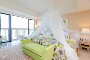糸满南方海滩酒店的一间卧室配有天蓬床和绿椅
