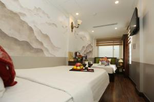 河内Golden Sail Hotel & Spa的酒店客房设有两张床,墙上挂有绘画作品