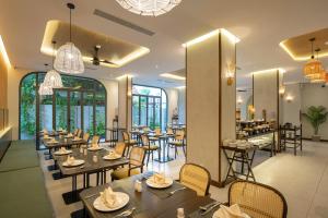 岘港Cozy Danang Boutique Hotel的餐厅设有桌椅和窗户。