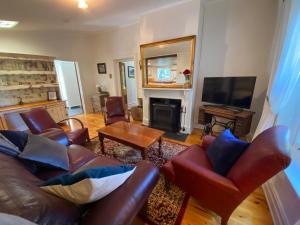 斯特灵Stirling Cottage的客厅配有皮革家具和壁炉