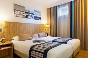 戛纳Citadines Croisette Cannes的酒店客房设有两张床和窗户。