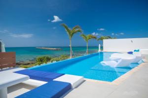 宫古岛Ronsard Resort IRABU的一个带椅子的游泳池,背景是大海