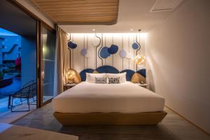 卡塔海滩Metadee Concept Hotel的一间卧室配有一张大床和蓝色床头板