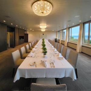 楚格Guggital Hotel Restaurant的长长的用餐室配有长桌子和椅子