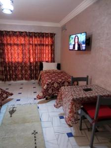 马拉喀什Marrakech Hôtel Résidence的一间卧室设有两张床,墙上配有电视。