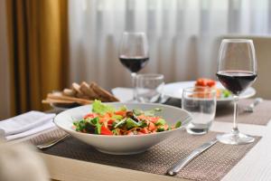菲乌吉圣乔治酒店的一张桌子,上面放着一碗沙拉和一杯葡萄酒