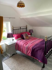 利默里克Katie’s Cottage的一间卧室配有一张带粉色和紫色床单的床