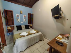 戈亚斯州上帕莱索波萨达瑞坎托格兰达巴斯酒店的卧室配有一张床,墙上配有电视。