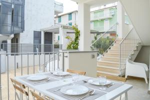 皮内托Homiday - Residenza Caravelle的阳台上配有白色的桌椅,设有楼梯