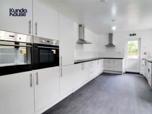 伯明翰Kunda House Gillotte的白色的厨房配有白色橱柜和黑色家电